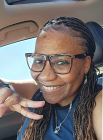 A woman with glasses and braids in the back of her car.