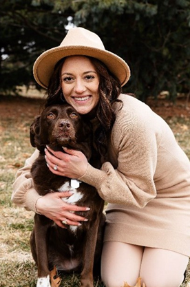 A woman holding her dog in the grass.