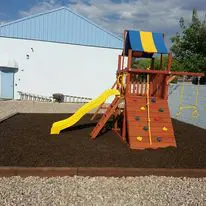 A playground with a slide and swing set in the yard.