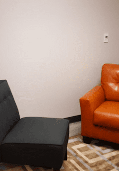 A black chair and an orange couch in a room.