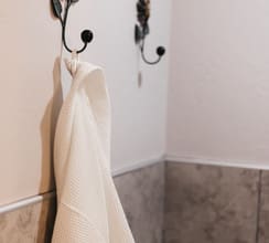 A white robe hanging on the wall in a bathroom.