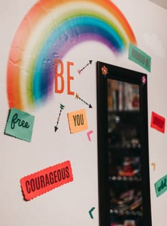 A rainbow with colorful stickers on the wall.