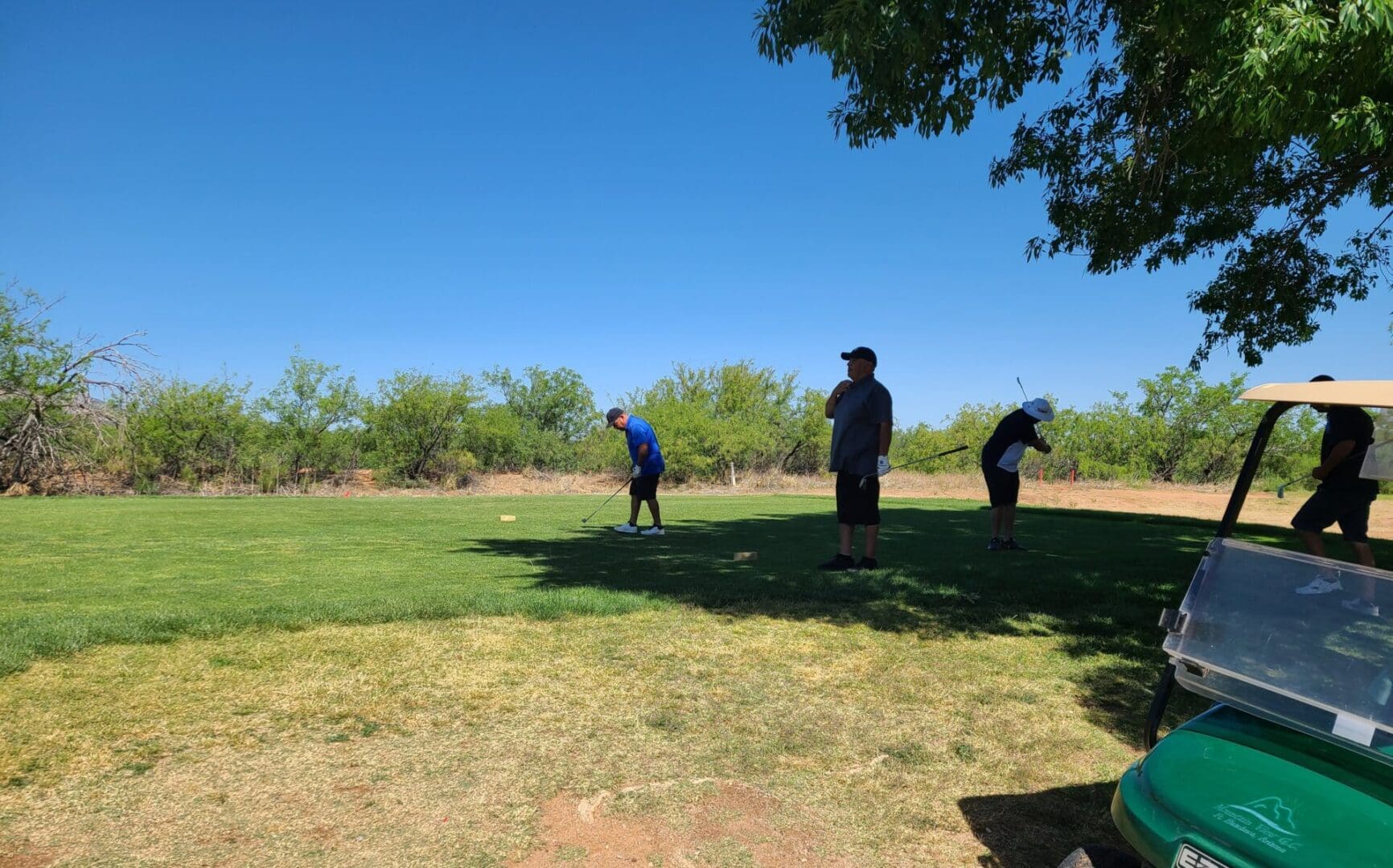 Three people playing golf on a sunny day.