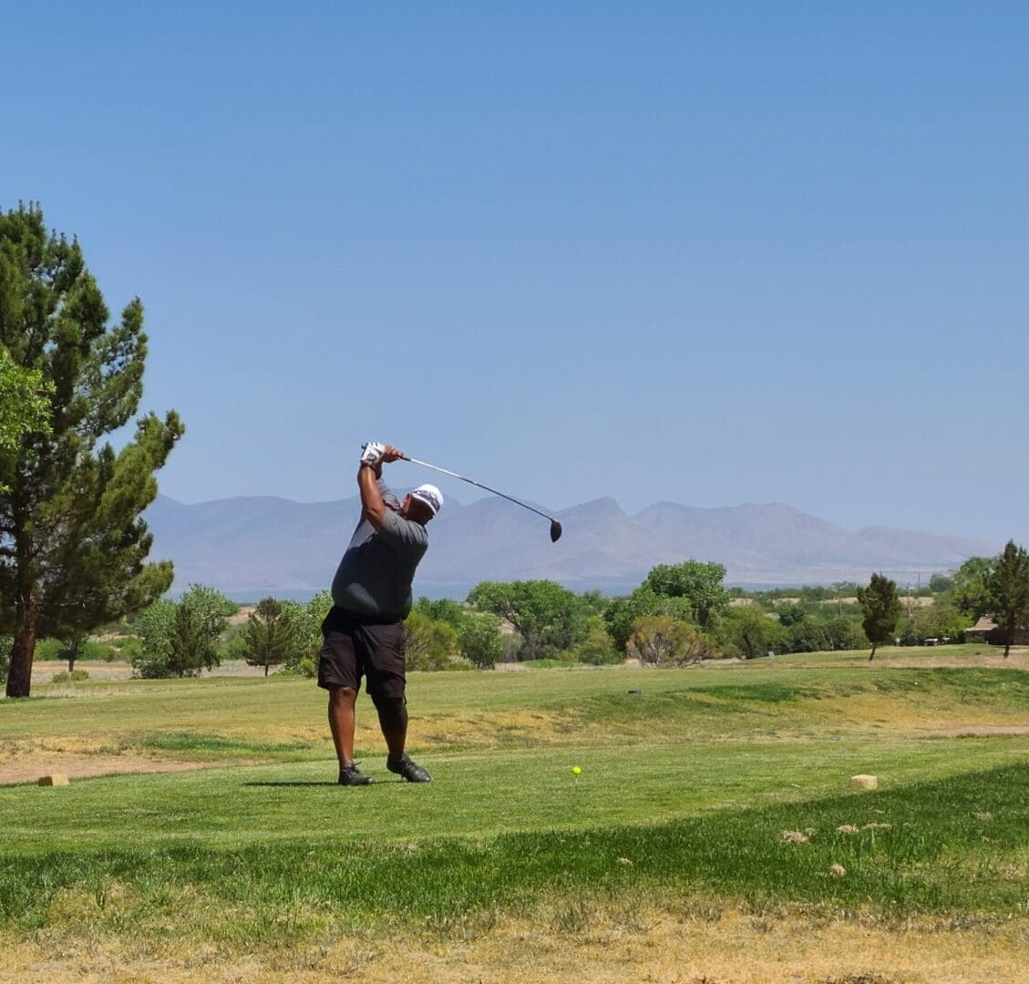 A man swinging at a golf ball on the course.
