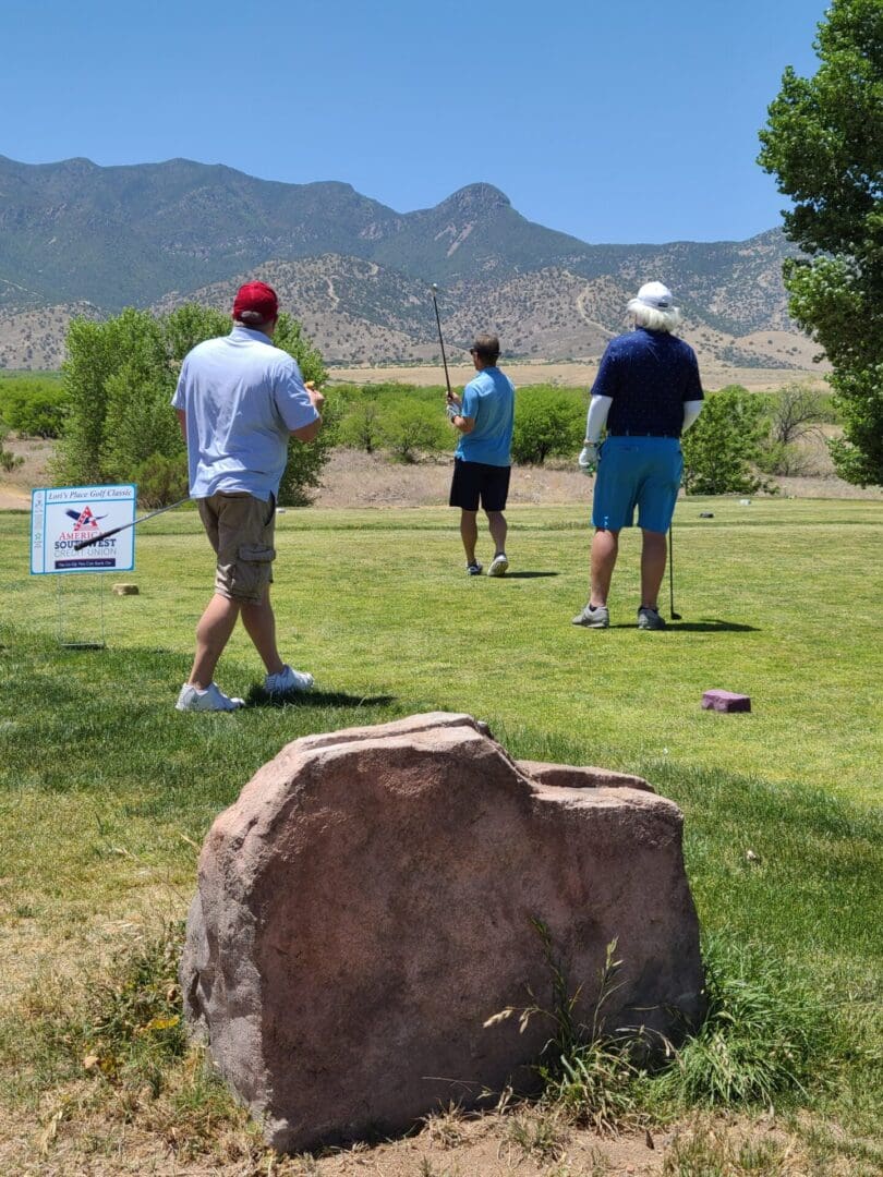 Three people are playing golf on a sunny day.