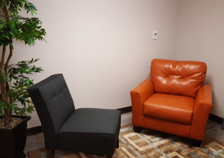A black chair and orange couch in an empty room.
