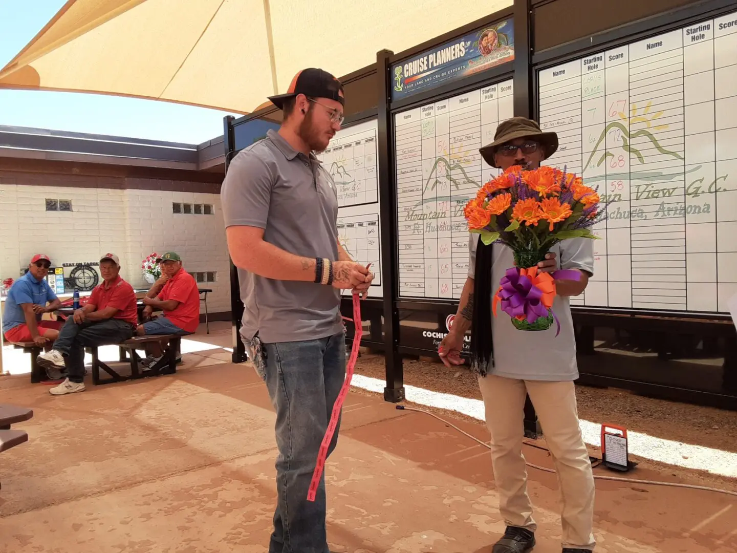 A man standing next to another man holding flowers.