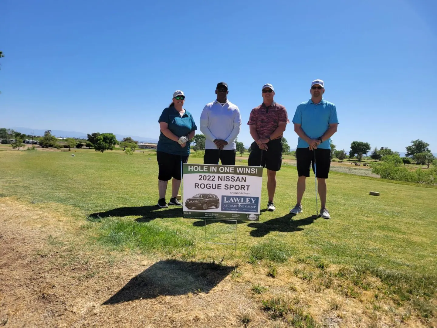 Four men standing in a field holding golf clubs.